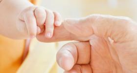 Mano de una persona adulta sosteniendo la mano de un niño